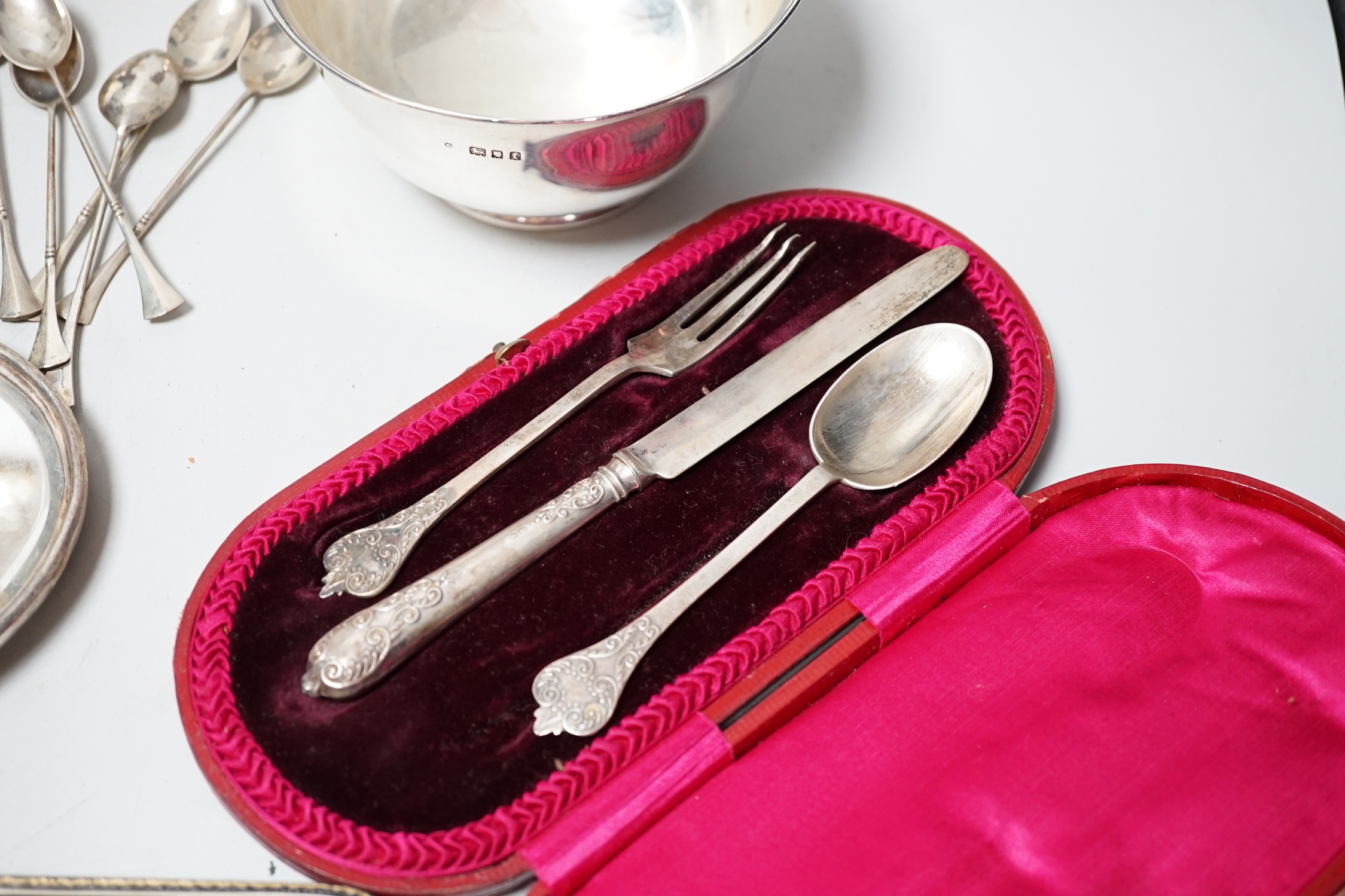 A George IV silver meat skewer, Robert Poulden, London, 1821, 30cm and other sundry silver including a George V bowl, a cased christening trio, pair of dwarf candlesticks, cased butter dish and knife, hand mirror etc.